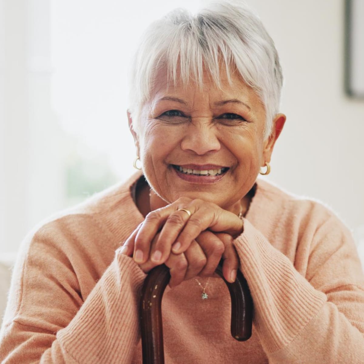 Older woman with both hands and her chin on a cane