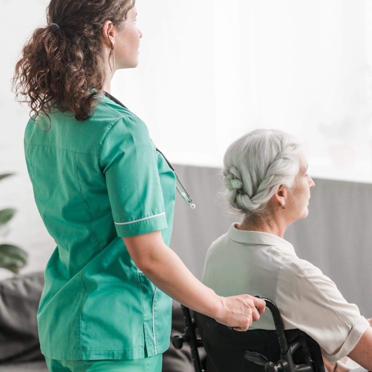 Caregiver pushing an older woman in a wheelchair